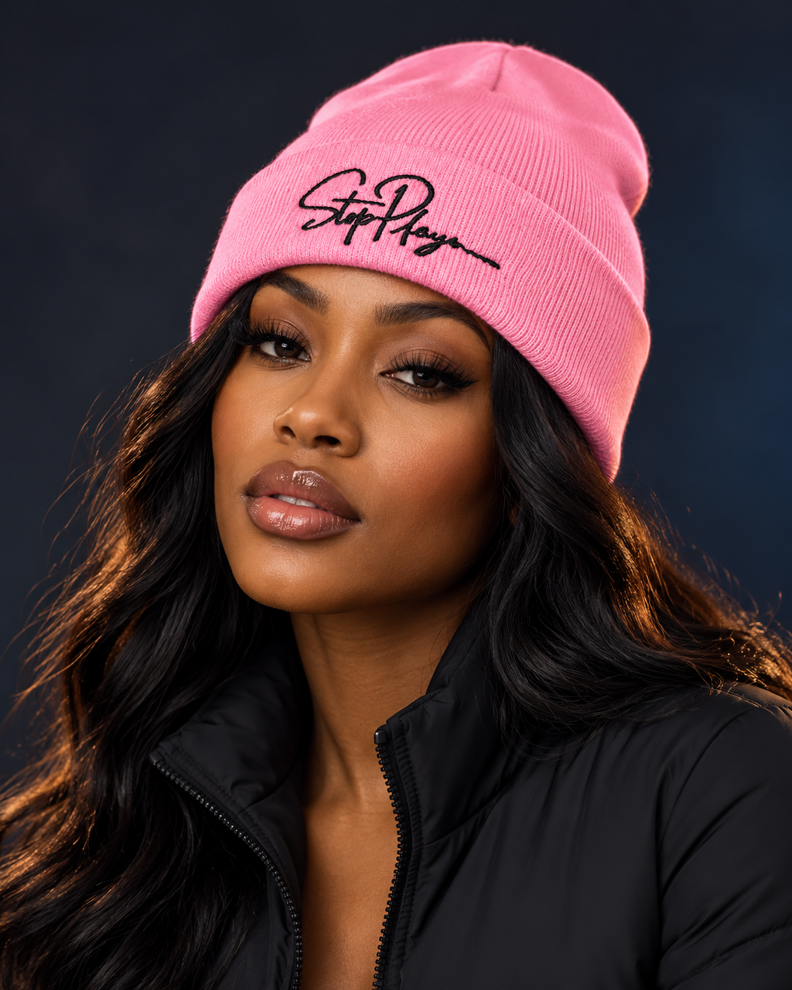 Adult model wearing the pink StopPlayn Signature Beanie with black embroidery